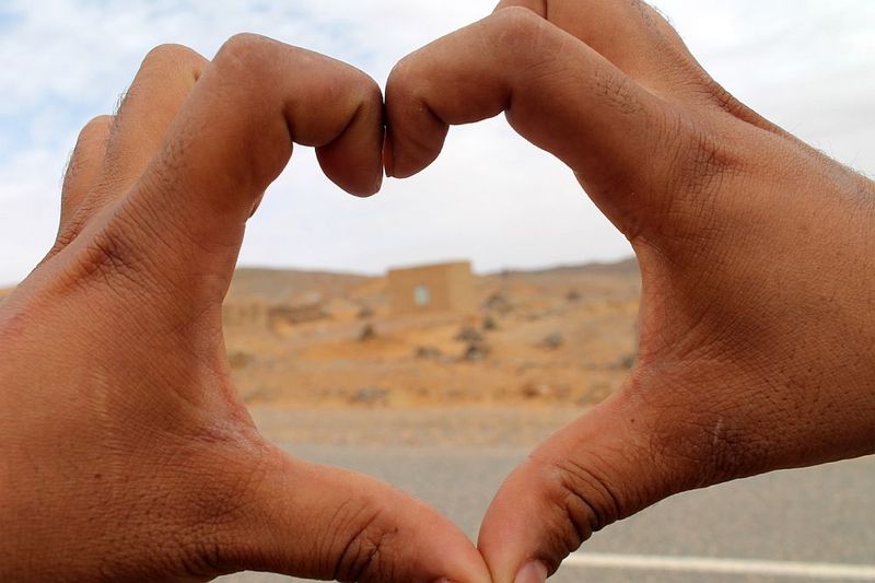 Foto zweier zu einem Herz geformten Hände mit einem unscharfen Blick in die Ferne